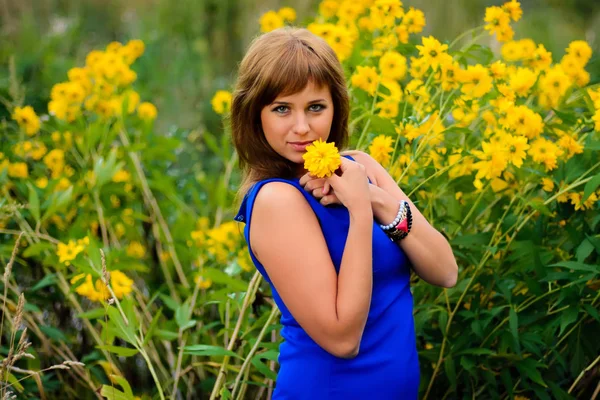 Ragazza in abito contro i fiori gialli in fiore — Foto Stock