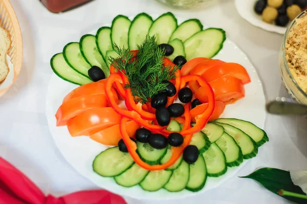 Нарезка овощей помидоров, огурцов, перца с оливками и укропом на тарелке — стоковое фото