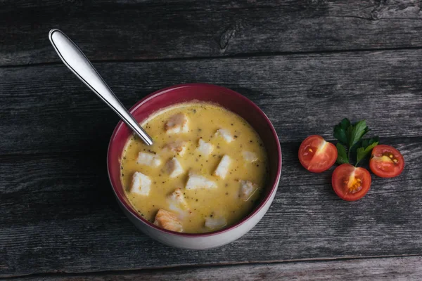 Gemüsekürbiscremesuppe mit Crackern in einer Schüssel mit einem Löffel auf einem Holztisch mit Petersilie — Stockfoto