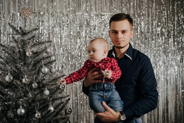 Figlio e padre. Un bambino tra le braccia di suo padre all'albero di Natale — Foto Stock