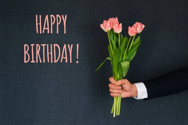 Bukiet różowych tulipanów w dłoni mężczyzny. Kartka z pozdrowieniami z tekstem Happy Birthday — Zdjęcie stockowe