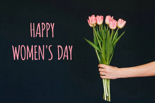 Ευχετήρια κάρτα με την επιγραφή ευτυχισμένη ημέρα της γυναίκας. Μπουκέτο λουλουδιών ροζ τουλίπας στο χέρι μιας γυναίκας — Φωτογραφία Αρχείου