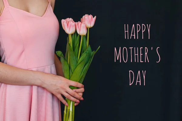 Buquê de flores de tulipas rosa nas mãos de uma menina. Cartão de saudação com texto Feliz Dia das Mães — Fotografia de Stock