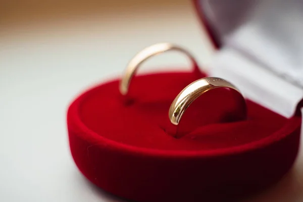 Пара золотых обручальных колец лежат в красной коробке крупным планом Лицензионные Стоковые Фото