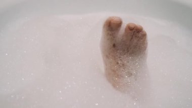 güzel esmer kız cinsel bacağını okşur ve köpük ile banyoda şarkı