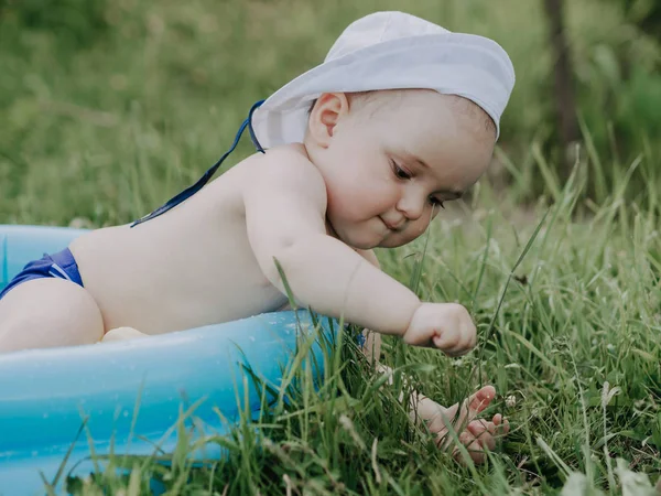 Egy nyári napon egy kék felfújható medencében játszó kisfiú — Stock Fotó