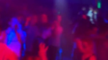 bir gece kulübünde dans pistinde dans eden insanların bir kalabalığın bulanık siluetleri