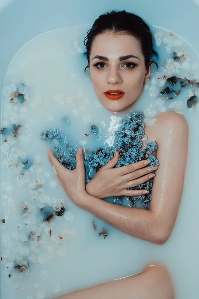 Retrato de uma bela menina nua relaxante e descansando no banho com leite e flores de lilás e maçã — Fotografia de Stock