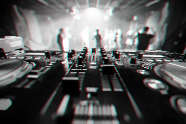 Музыкальное оборудование DJ в ночном клубе крупным планом с размытым фоном танцующих людей — стоковое фото