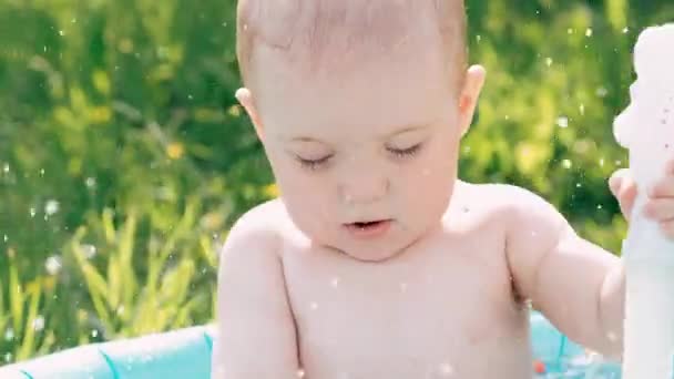 Funny Boy baby badar och leker med stänk av vatten i en uppblåsbar pool — Stockvideo