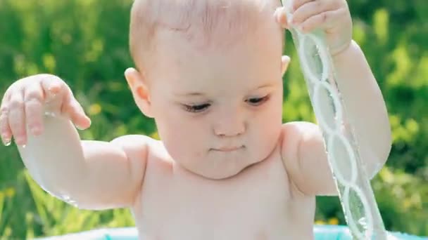 Menino pequeno que joga na piscina inflável em um verão ensolarado — Vídeo de Stock