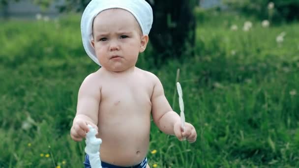 Маленький мальчик разбивает игрушку на летнем поле — стоковое видео
