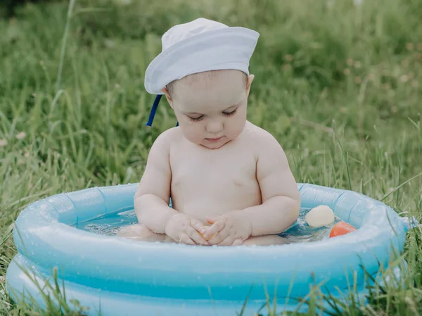 Aranyos Baby fiú, kék felfújható medence fröccsenő nyári nap — Stock Fotó