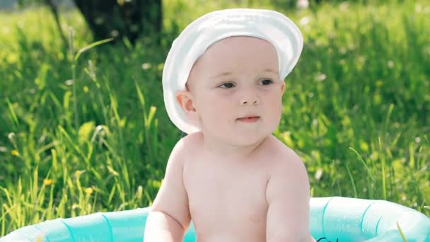 Счастливый маленький мальчик купается в надувном бассейне пузырьков летом в солнечный день — стоковое видео