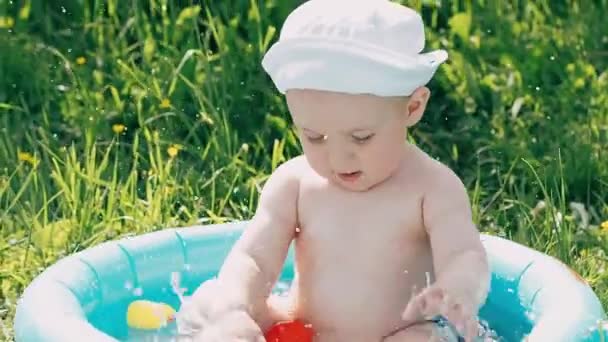 Kleine baby jongen spelen en lachen zwemmen in de opblaasbare zwembad in de zomer — Stockvideo