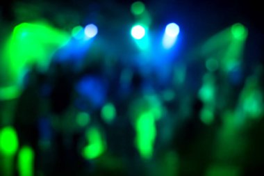 renkli spot ışıkları altında dans pistinde bir gece kulübünde dans eden bir grup insanın bulanık siluetleri