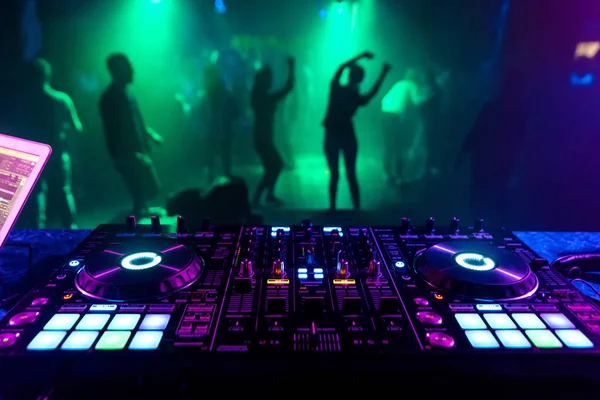 DJ music mixer in a booth in a nightclub on a blurred background of dancing  people Stock Photo by ©alexkoral 285491836