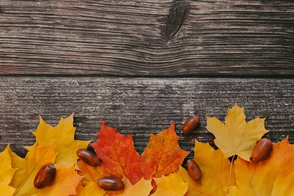 Drewniane tło z jesiennym, suchym, pomarańczowym liści klonu i żołędzi — Zdjęcie stockowe