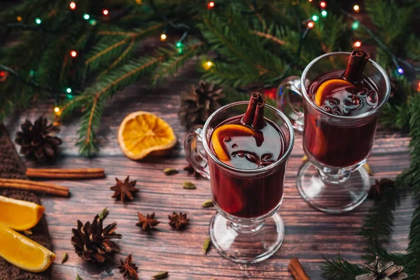 Vino caliente en copas de vidrio con rodajas de naranja, palitos de canela y especias con decoración navideña — Foto de Stock