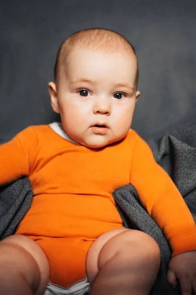 Egy narancssárga Body kisfiú ül — Stock Fotó