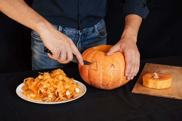 Jacks Halloween dyni. Ręce mężczyzny z nożem cięcia pomarańczowy dyni — Zdjęcie stockowe
