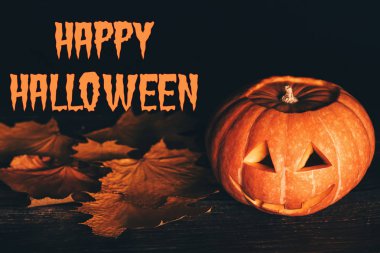 Akçaağaç yaprakları ile siyah bir arka plan üzerinde Jacks kabak fener