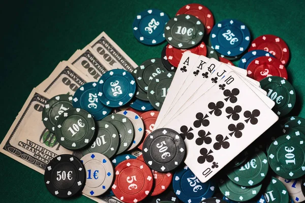 Kaarten met een Royal flush op een stapel chips en geld dollars in een spelletje poker — Stockfoto