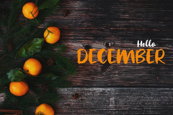 Ramas de abeto y mandarinas sobre un fondo de madera y el texto Hello December — Foto de Stock