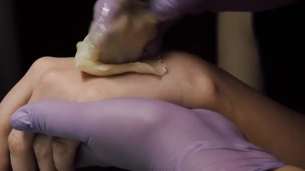 Профессиональный косметолог удаляет волосы с горячей сахарной пастой на пальцах женщины — стоковое видео