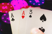 karty s jedním párem es v rukou pokerového hráče na pozadí herních žetonů