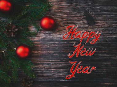 Yeni yılınız kutlu olsun. Köknar dalları ve kırmızı toplarla dolu ahşap bir arka planda.