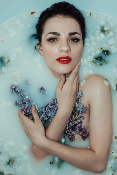 Bela menina relaxante e descansando no banho com leite e flores de lilás e maçã — Fotografia de Stock