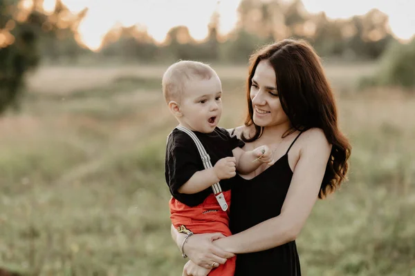 Joven madre caucásica con su hijo en brazos en el campo de verano —  Fotos de Stock