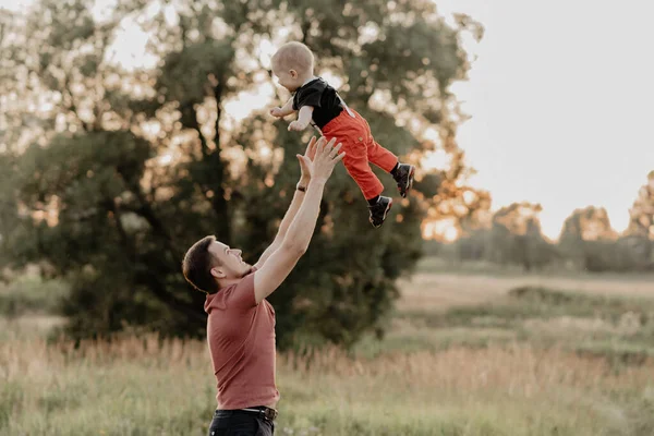 Papá lanza a su pequeño hijo al campo en el verano —  Fotos de Stock