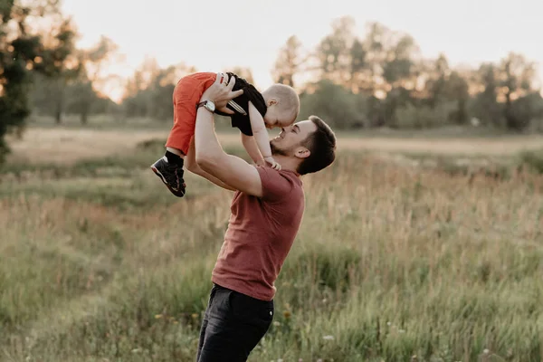 Feliz papá y su hijo sonríen y juegan en el campo de verano al atardecer —  Fotos de Stock