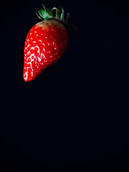Strawberry ripe juicy red berry falling flying on a black background — Stock Photo, Image