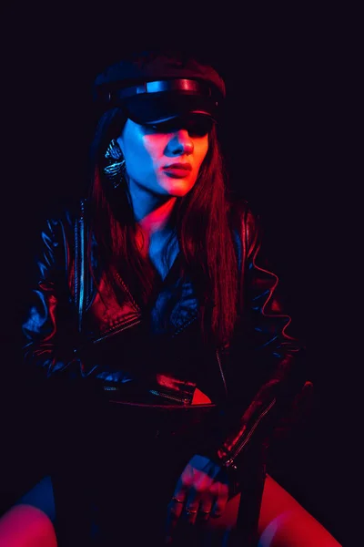 Fashionable portrait of a stylish girl in a leather jacket and cap with a neon light — Stock Photo, Image