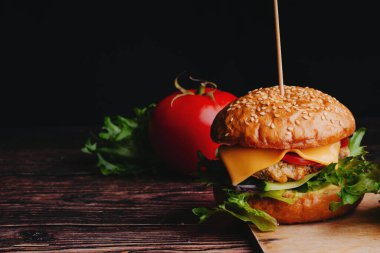 Etli, peynirli, marullu, domatesli ve soğanlı sulu hamburger.