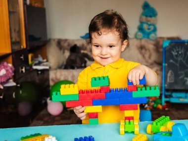 Mutlu çocuk evde renkli bloklarla oynuyor.