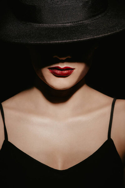 Stylish Studio portrait of a girl in a black hat and dress on a dark background