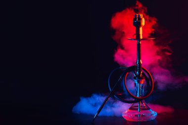 Cam mataralı nargile ve masada renkli dumanlı metal kase shisha.