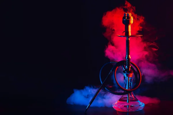 Hookah ze szklaną kolbą i metalową misą shisha z kolorowym dymem na stole — Zdjęcie stockowe