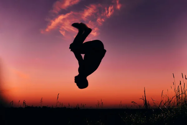 Silhouette d'un homme faisant un saut périlleux en été dans la nature — Photo