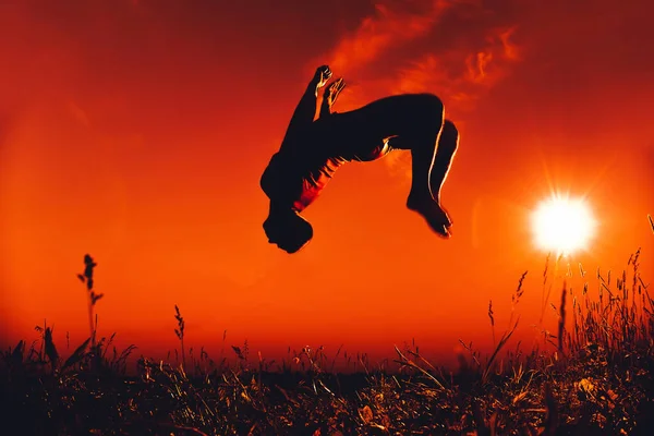 Человек прыгает и делает сальто назад летом в природе — стоковое фото