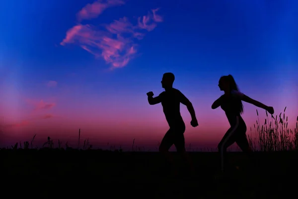 Силуэты бегущих по утрам мужчин и девушек — стоковое фото