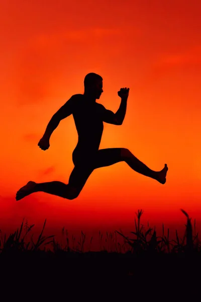 Silhouette d'un gymnaste masculin effectuant un entraînement de saut dans la nature — Photo