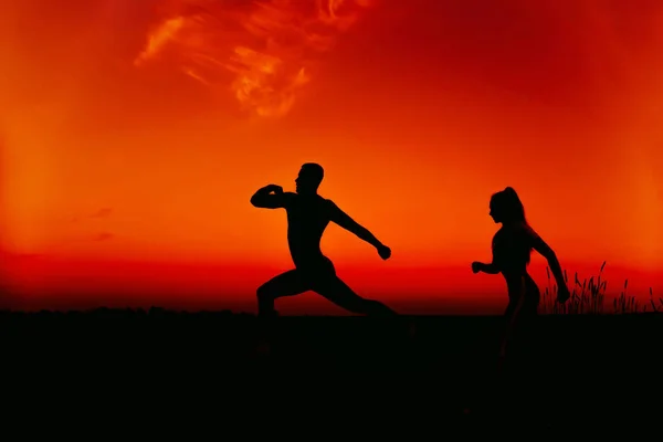 Silhouettes d'un couple courant dans la nature en été au coucher du soleil — Photo