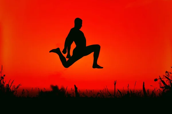 Silhouette d'un homme sportif sautant haut dans la nature — Photo