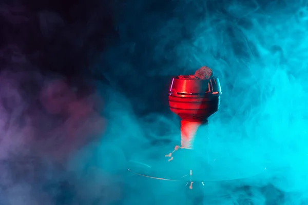 Carbones rojos de shisha calientes en un cuenco de narguile de metal sobre un fondo de humo multicolor — Foto de Stock