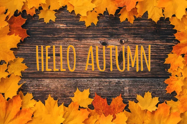 Inscripción Hola otoño sobre un fondo de madera con un marco de hojas de arce naranja —  Fotos de Stock